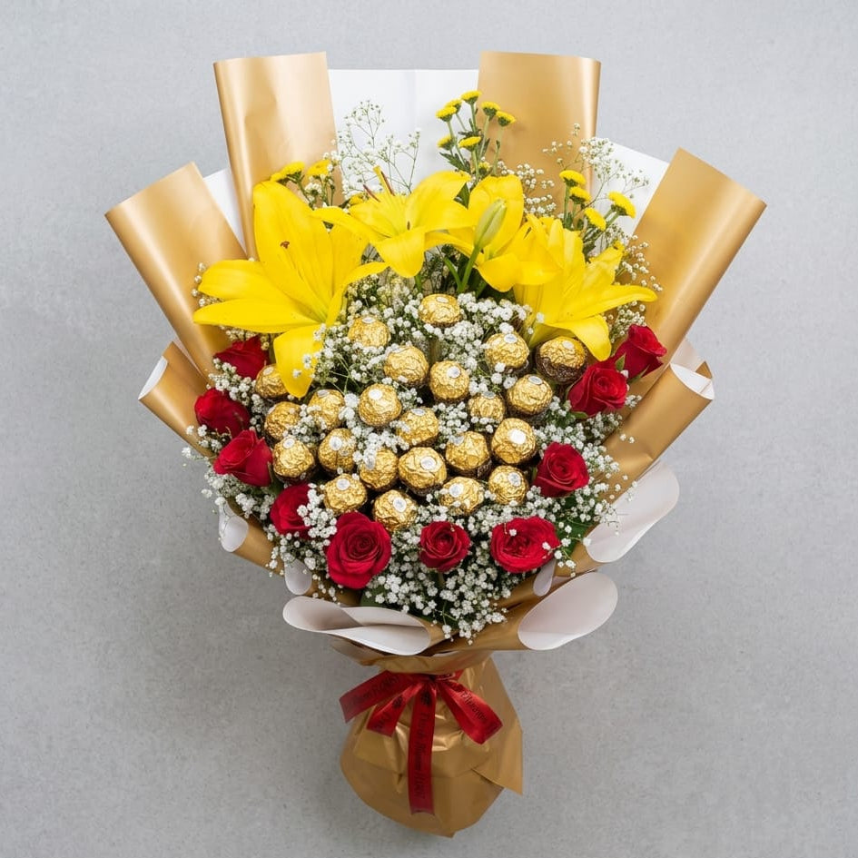 Bouquet of flowers with yellow lilies, red roses, and Ferrero rocher chocolate on a gray background